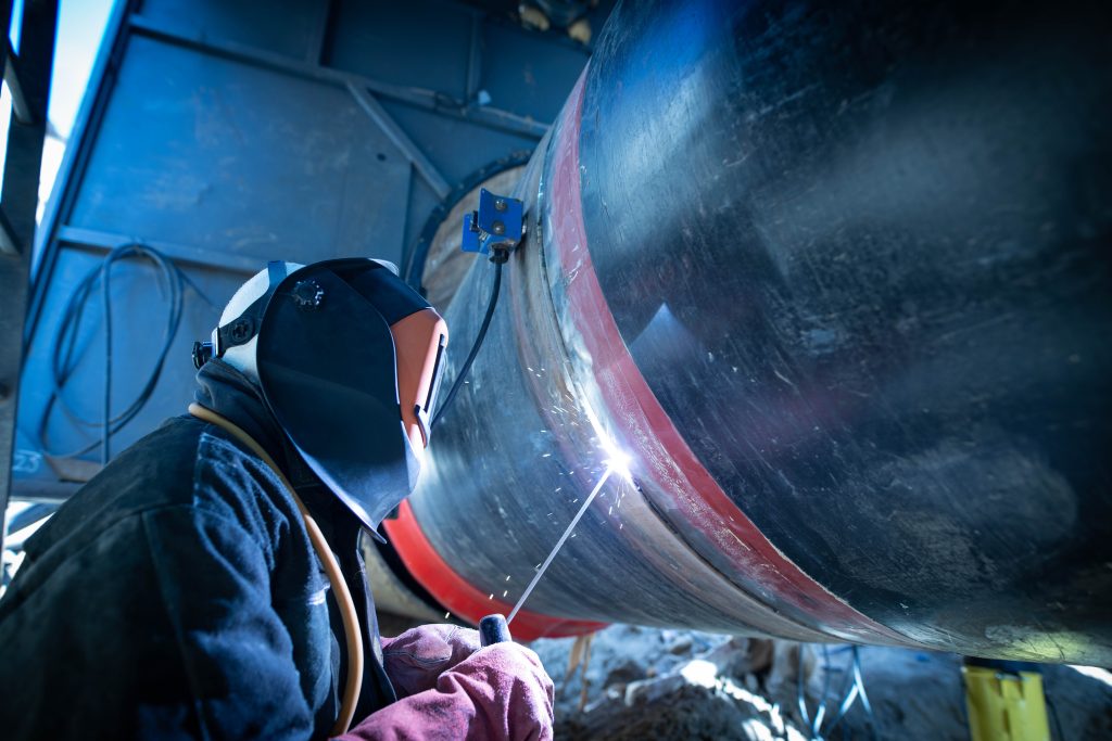 Professional welder welding pipe on a pipeline construction